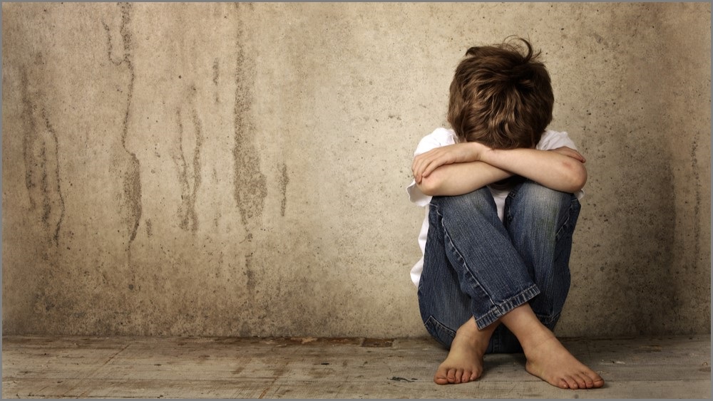 Boy sitting alone, hiding his face.